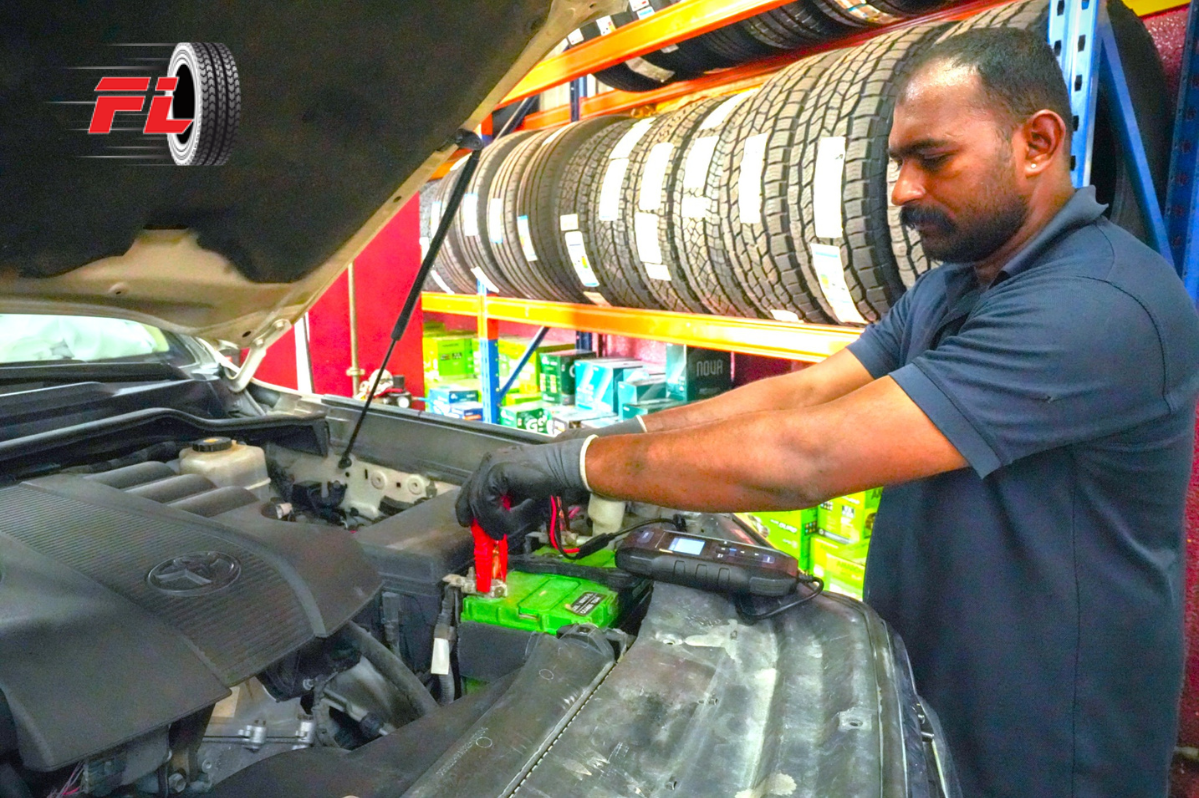 "Fastlane Tyres technician testing and servicing a car battery at the workshop in Dubai."